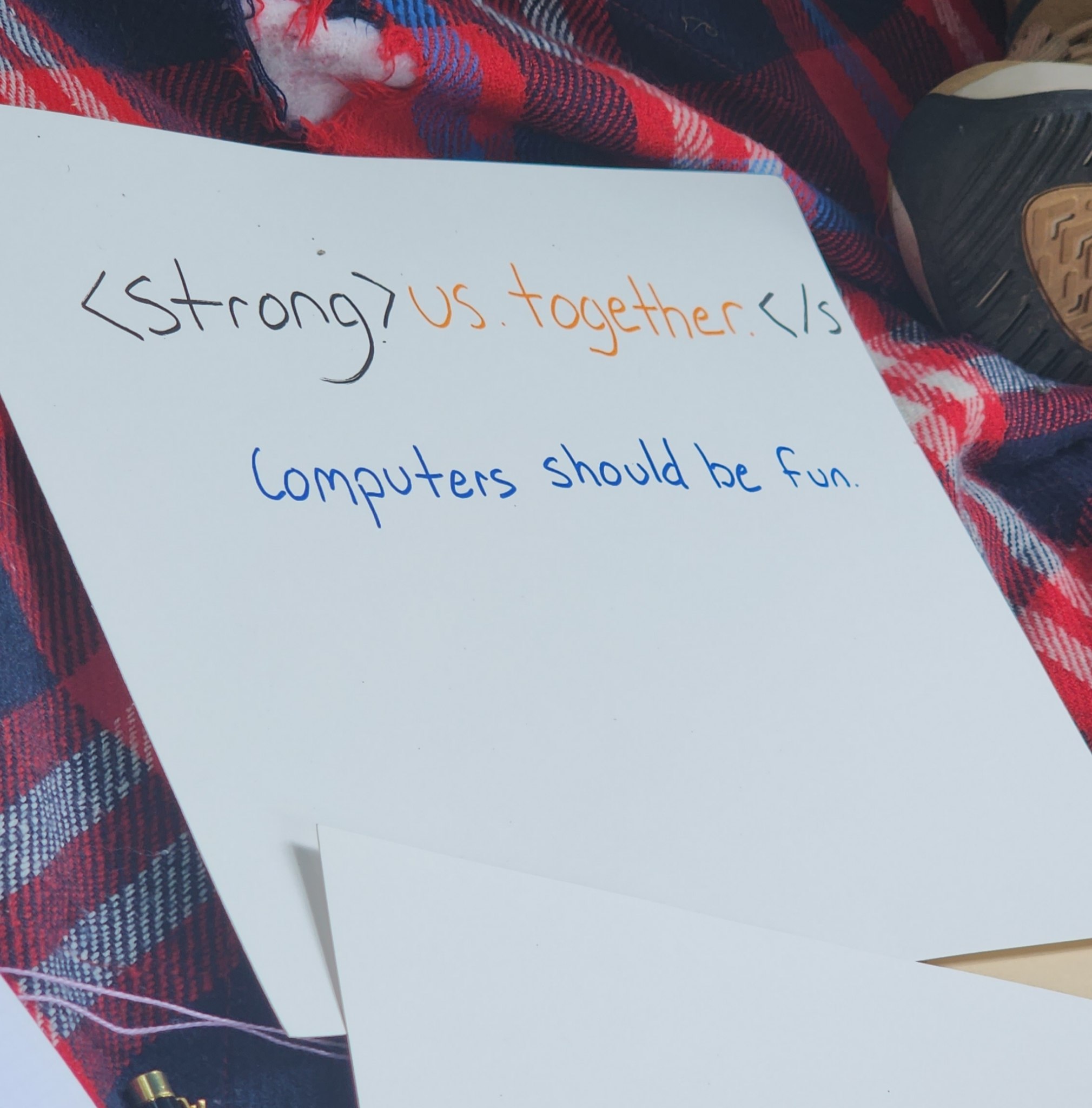 A piece
        of paper with a handwritten note stating that we are strong together, with a reference to the HTML strong tag.
        Beneath it, a statement that computers should be fun.